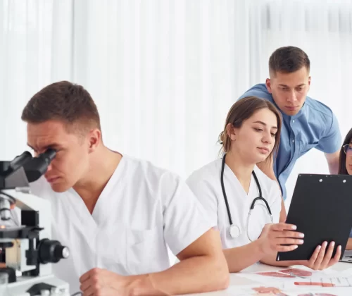 man with microscope group young doctors is working together modern office
